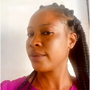 A woman with long braids and a pink shirt.